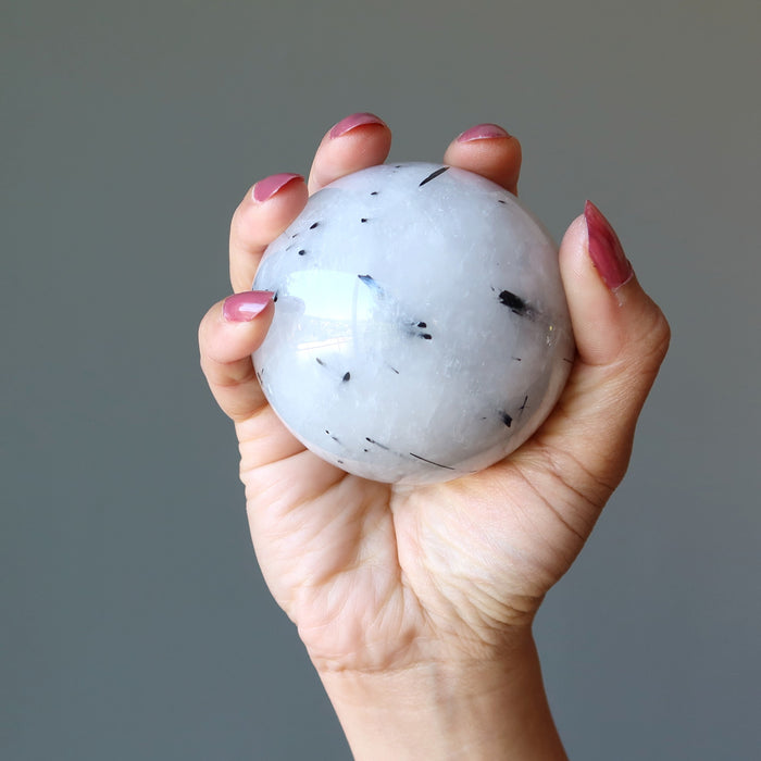 quartz tourmaline sphere in palm of hand