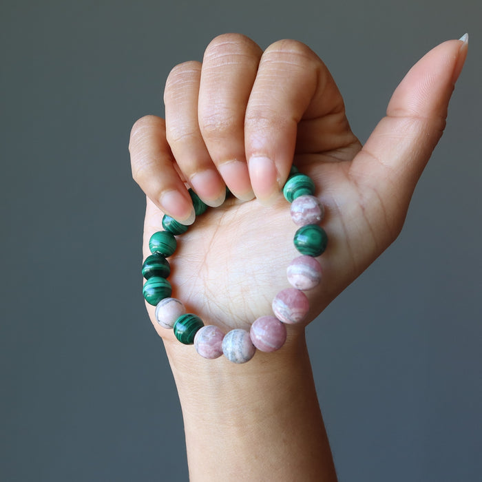 hand holding a rhodochrosite and malachite stretch bracelet