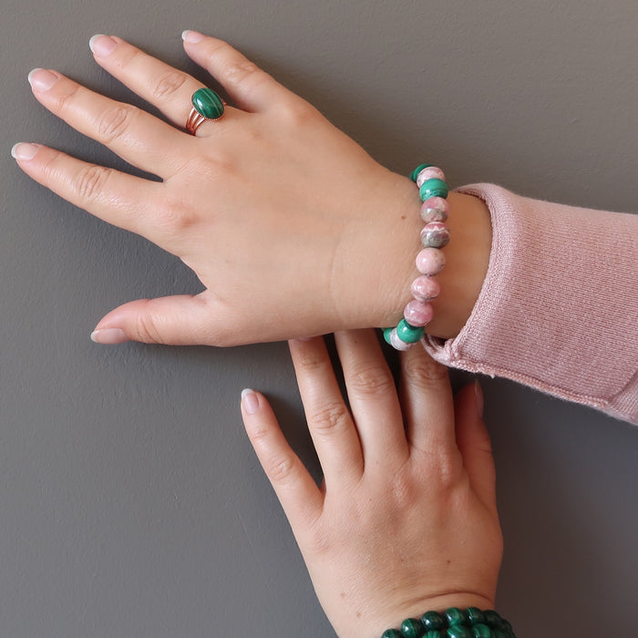 hand wearing rhodochrosite and malachite stretch bracelet and a malachite copper ring