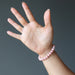 hand wearing rhodochrosite round beaded stretch bracelet
