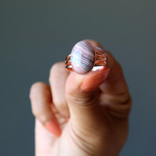 hand holding pink rhodochrosite oval in adjustable copper ring