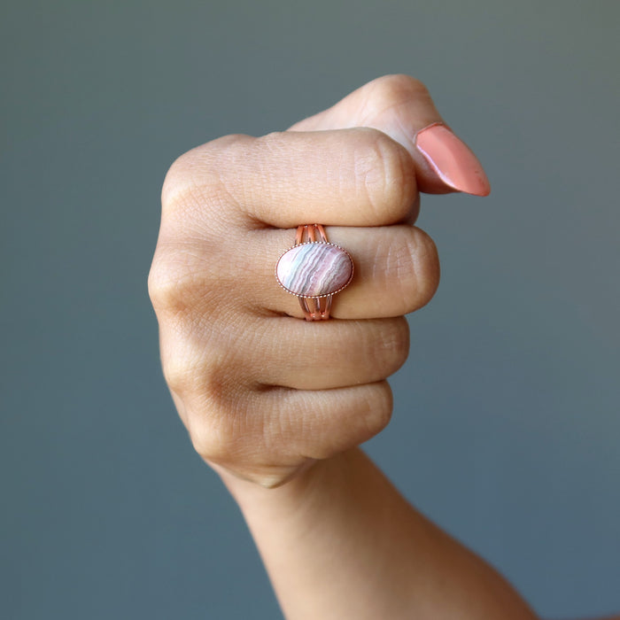 hand wearing pink rhodochrosite oval in adjustable copper ring