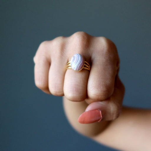 hand wearing rhodochrosite oval in gold adjustable ring