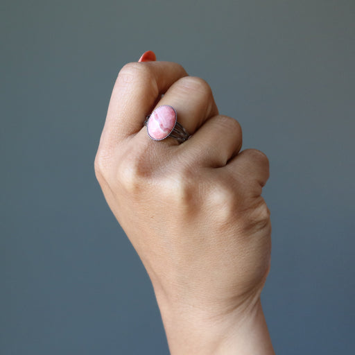 hand wearing pink rhodochrosite oval in gunmetal adjustable ring
