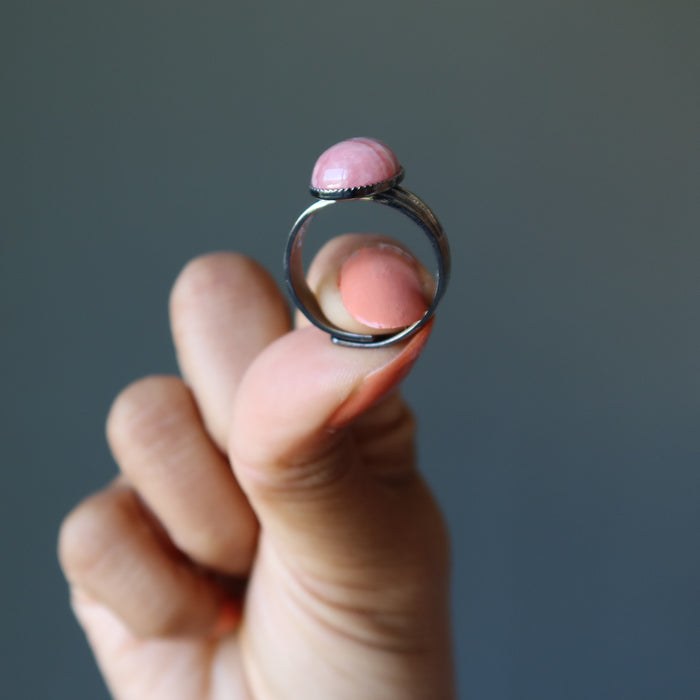 hand holding pink rhodochrosite oval in gunmetal adjustable ring