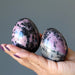 two rhodonite eggs in hand