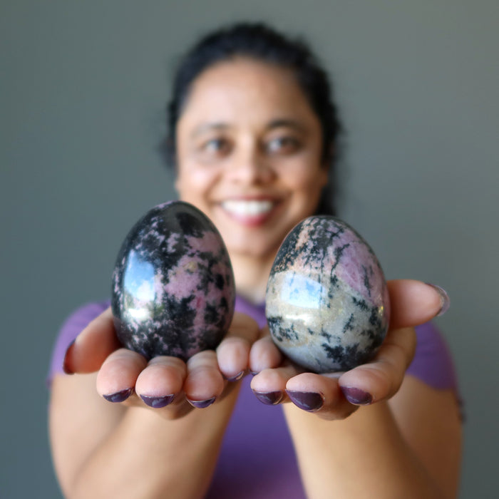 woman holding two rhodonite eggs