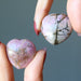 hand holding two rhodonite hearts