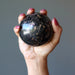 pink and black rhodonite sphere in hand