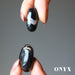 hands holding black and white onyx tumbled stones