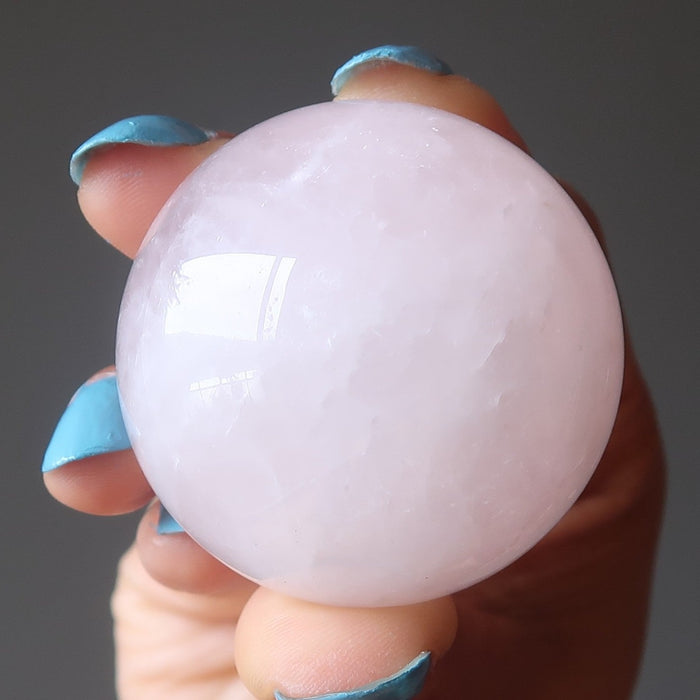 hand holding pink rose quartz crystal ball