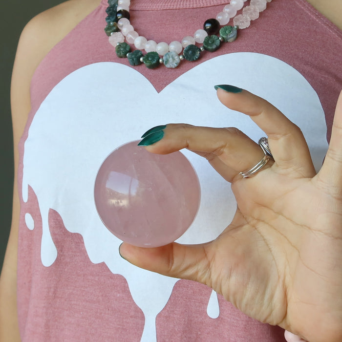 rose quartz ball held against a heart printed tank top