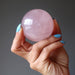 hand holding a rose quartz sphere