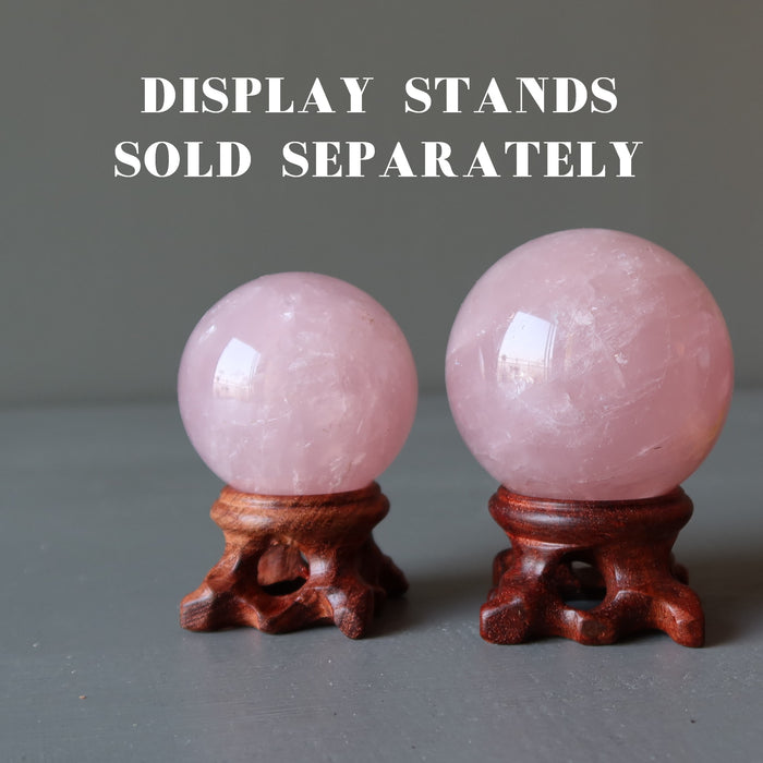two rose quartz spheres on wood display stands, which are sold separately