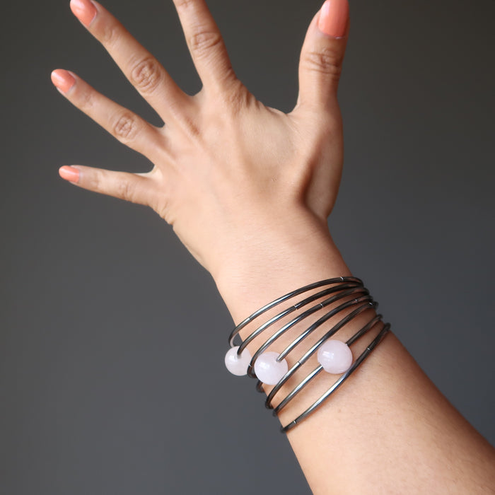 7 layer gunmetal bracelet with three statement beads in pink rose quartz being modeled on a woman