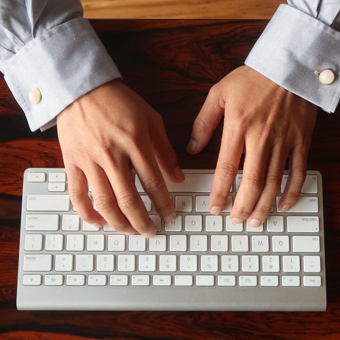 man typing wearing rose quartz gold cufflinks