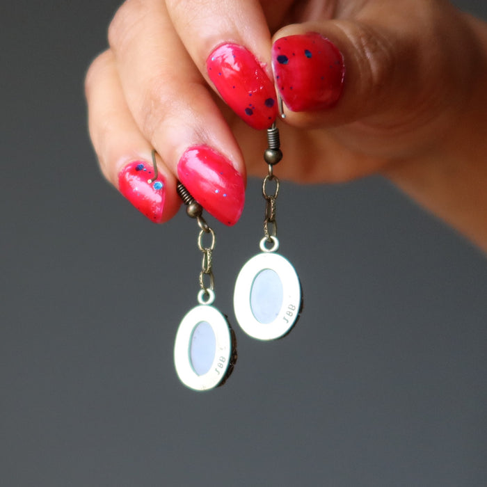 hands holding rose quartz earrings showing the backs