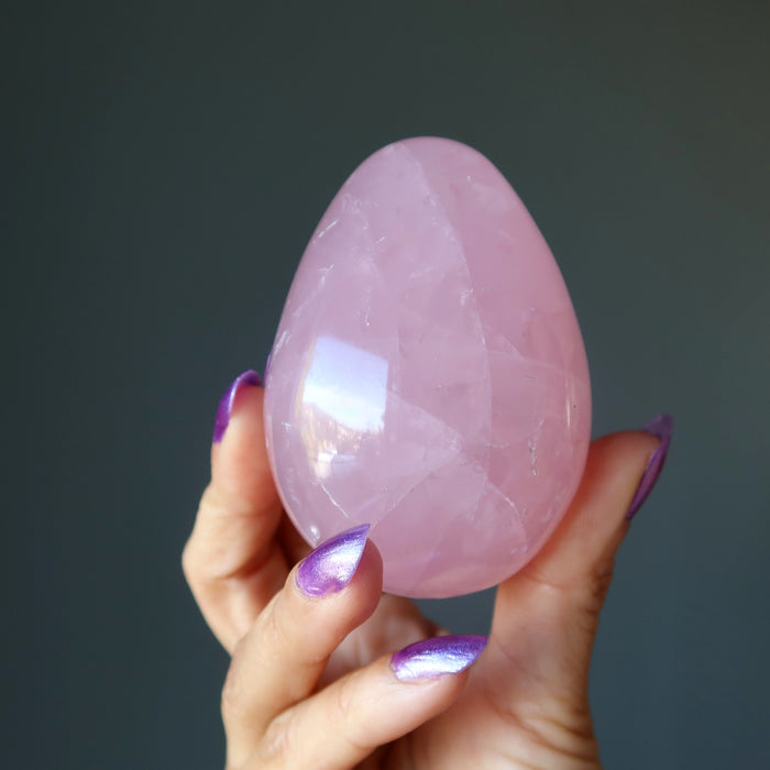 hand holding dark pink star rose quartz egg