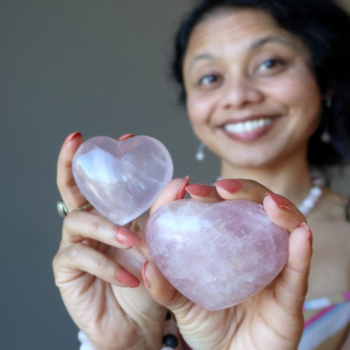woman holding two pink rose quartz crystal hearts
