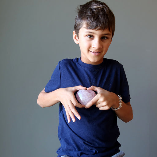 boy holding pink rose quartz crystal heart at his heart