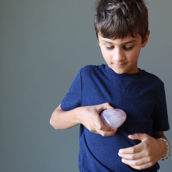 boy holding pink rose quartz crystal heart