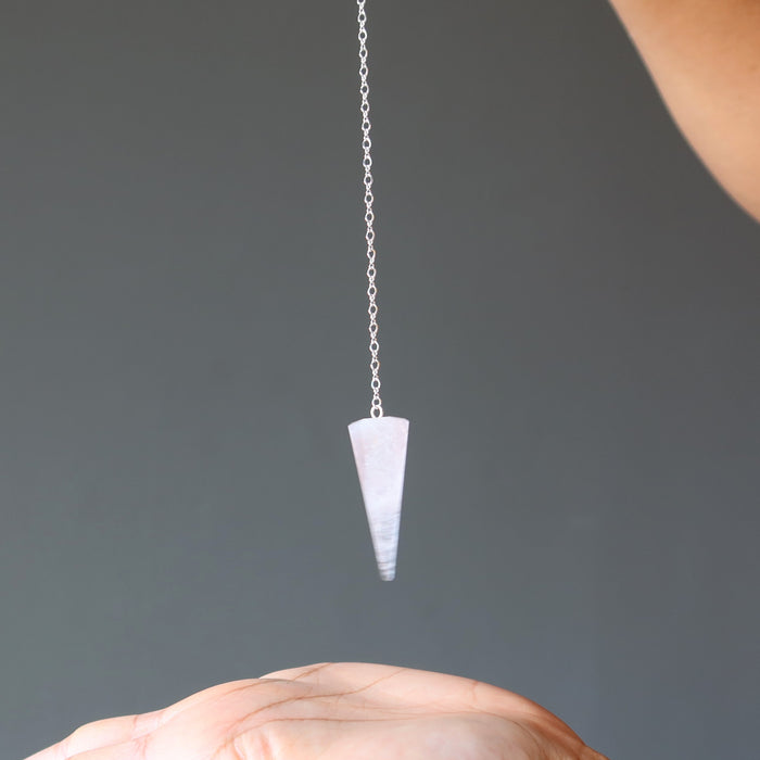 dowsing with a rose quartz pendulum over the palm of hand
