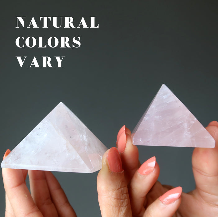 hands holding two pink rose quartz pyramids to show natural colors vary