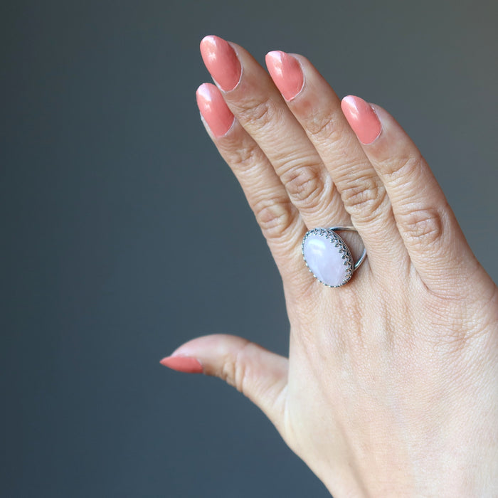 female hand wearing pink rose quartz oval in sterling silver adjustable ring