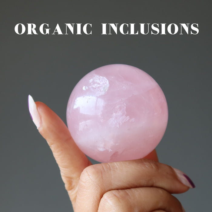 hand holding pink quartz sphere with organic inclusions