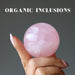hand holding pink quartz sphere with organic inclusions