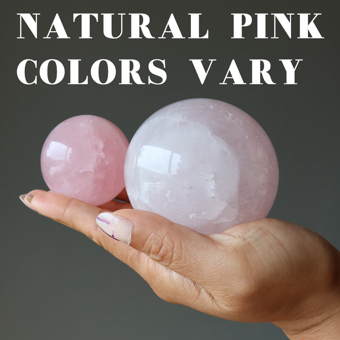 hand holding two rose quartz balls showing natural pink colors vary
