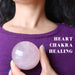 hand holding rose quartz sphere at the heart chakra 
