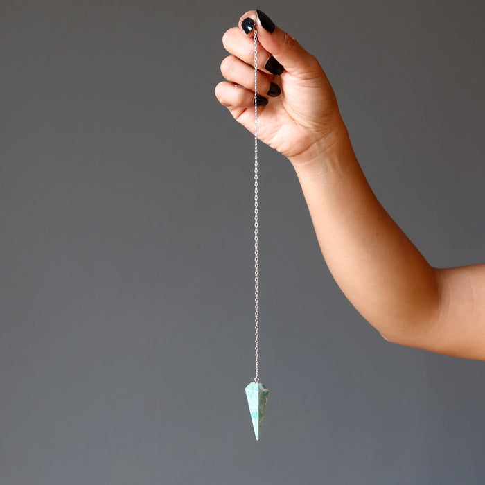hand holding ruby fuchsite pendulum on sterling silver chain