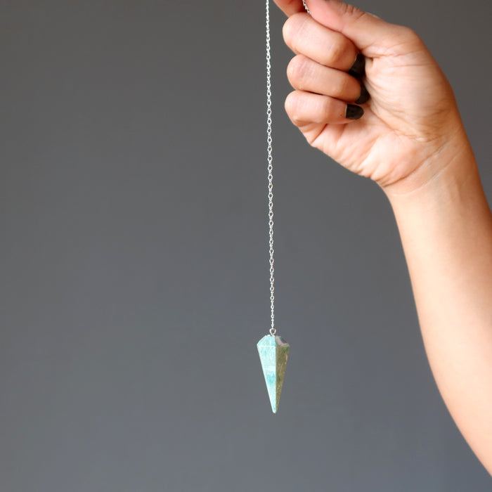 hand holding ruby fuchsite pendulum on sterling silver chain