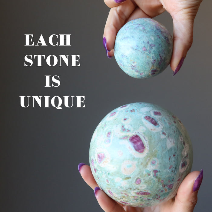 hands holding ruby fuchsite spheres to show each is unique