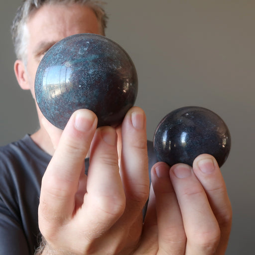 male model holding two ruby kyanite spheres