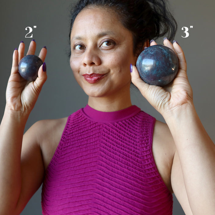 female model holding two ruby kyanite spheres