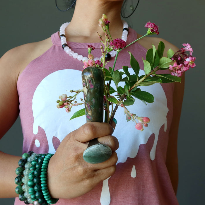 hand holding ruby zoisite tapered massage wand with pink flowers at the heart chakra