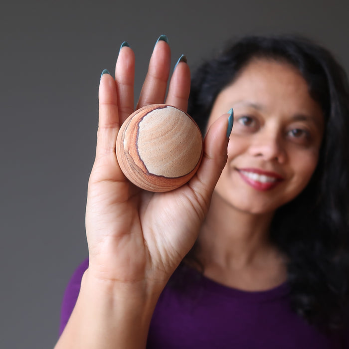 sheila of satin crystals holding a hand holding a sandstone sphere
