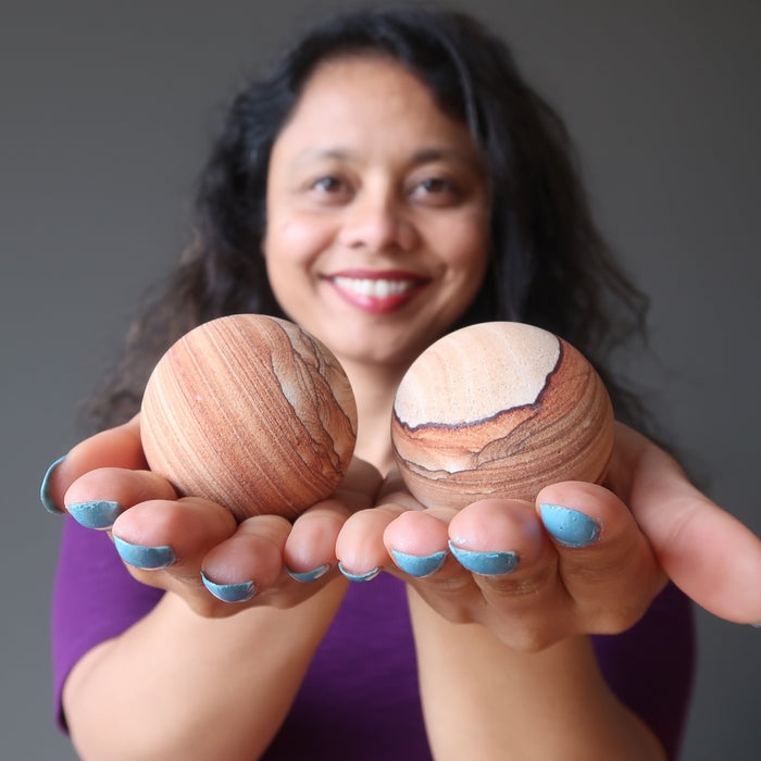sheila of satin crystals holding a sandstone ball in each palm of hand