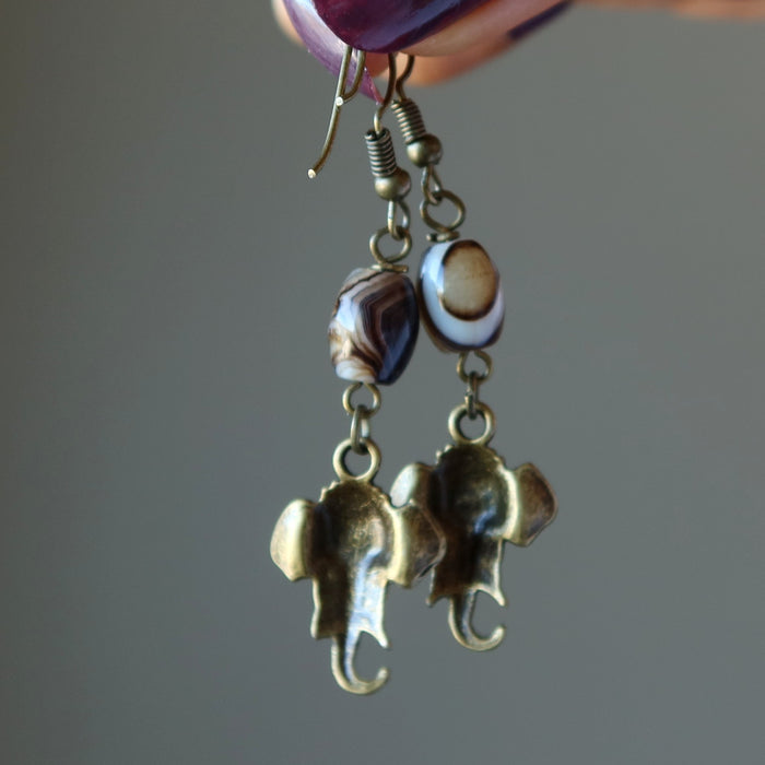 hand holding sardonyx elephant earrings showing back