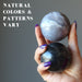 hand holding 2 sardonyx spheres to show natural colors and patterns vary