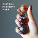 hand holding up three sardonyx spheres to show natural patterns vary