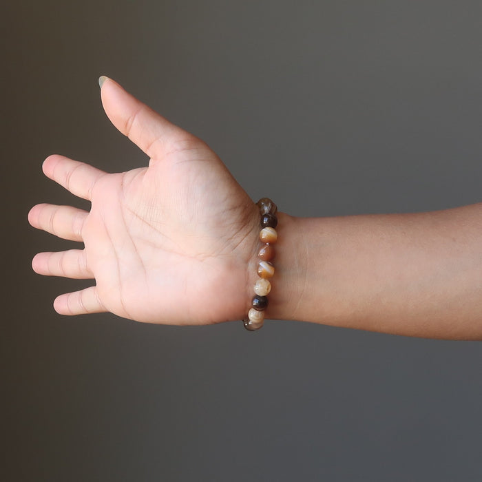 colorful brown and black sardonyx round gemstone bead bracelet on a hand model