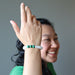 smiling model raises her hand to display selenite and malachite gemstone stretch bracelet
