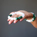 bright white selenite and green malachite bracelet in the palm of a woman's hand and two on her wrist
