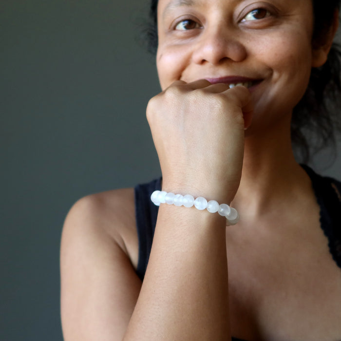 sheila of satin crystals with hand on chin wearing a white selenite beaded bracelet