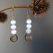 white selenite gold spiral dangle earrings hanging off a branch