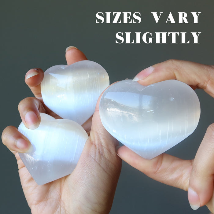 hand holding set of three white selenite hearts showing sizes vary slightly