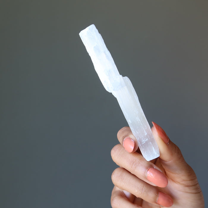 hand holding raw white selenite stick